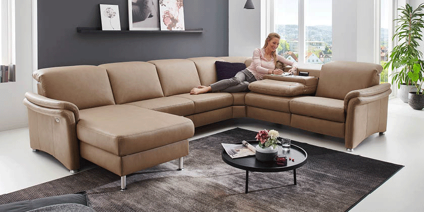 Frau sitzt auf beigem Leder-Ecksofa mit verstellbarer Rückenlehne